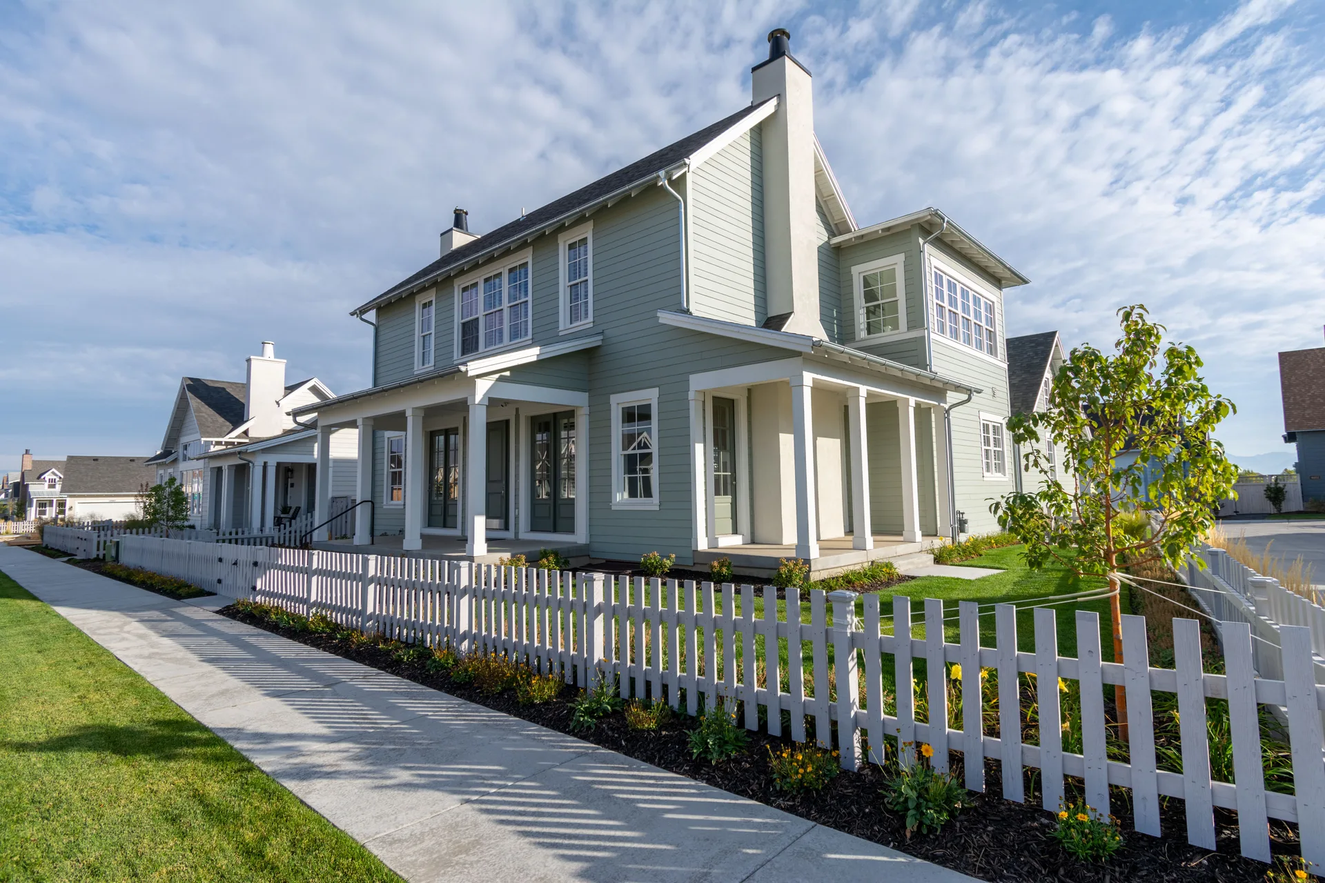White picket fence lining the front yard of a two-story home — fence installation in Greeley and Northern Colorado